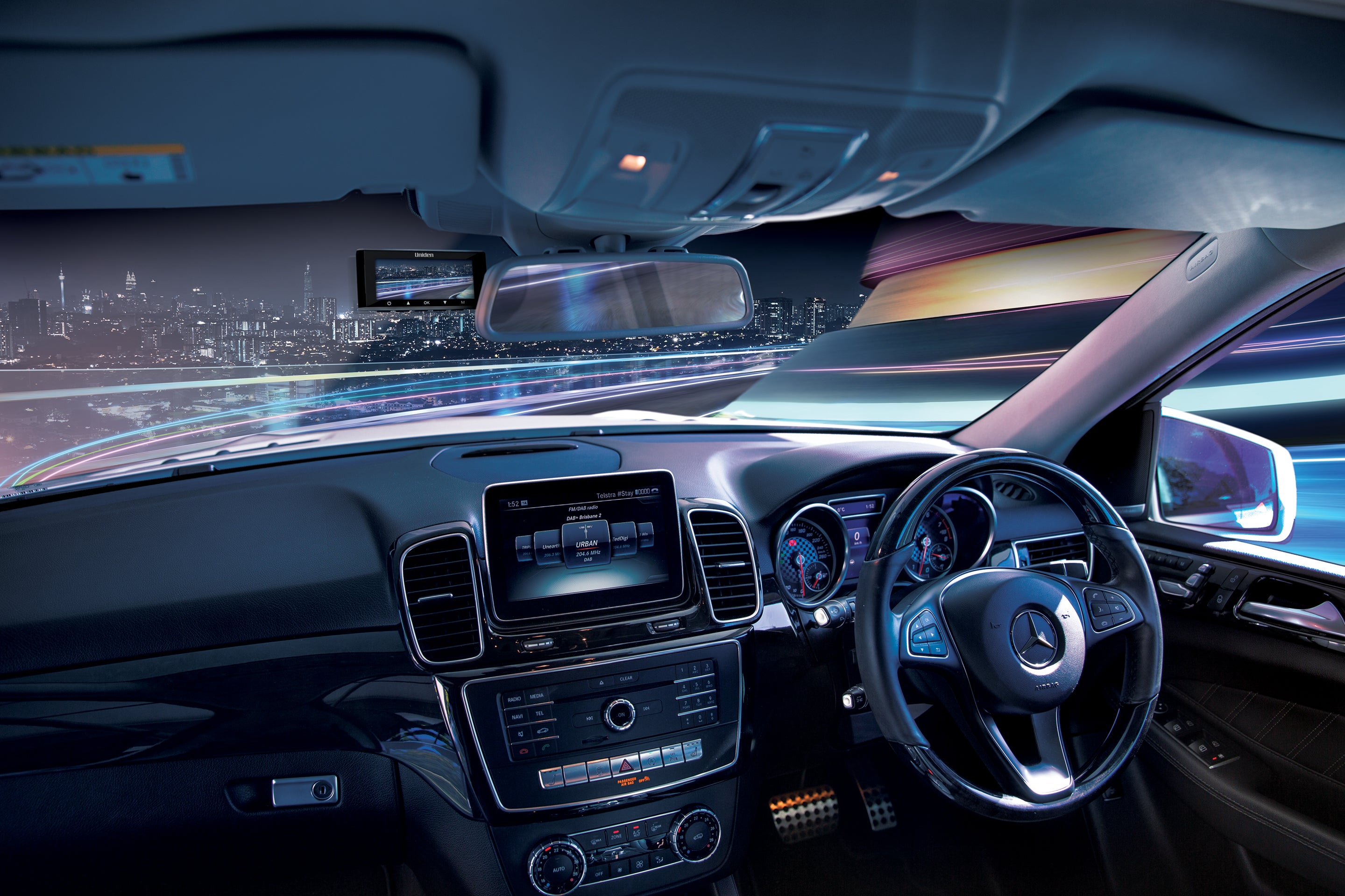 Car interior with digital display and steering wheel, cityscape outside the window