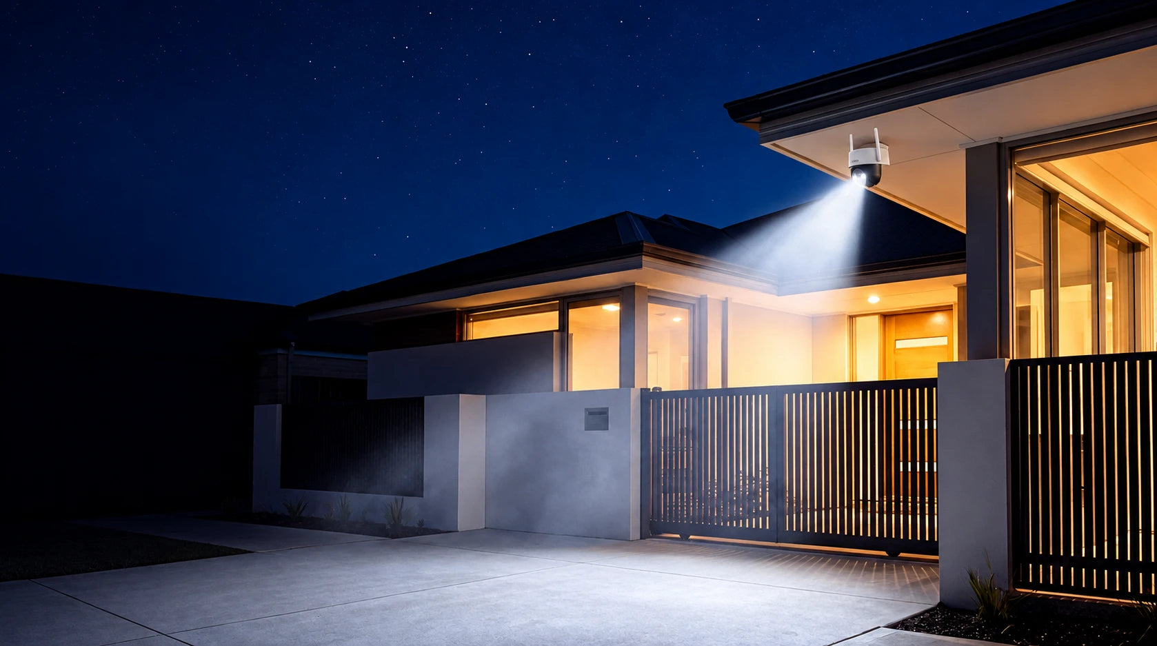 A SOLO X2K pan and tilt camera under the eave of a modern home, its spotlight beam lighting the driveway at night