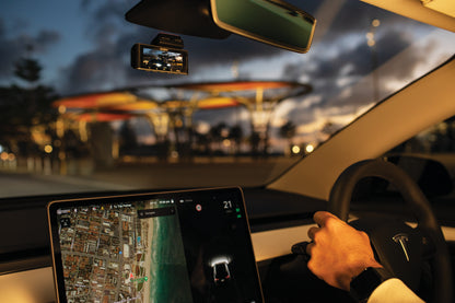 Uniden iGO CAM 90R dash cam mounted near the rear-view mirror during a sunset drive