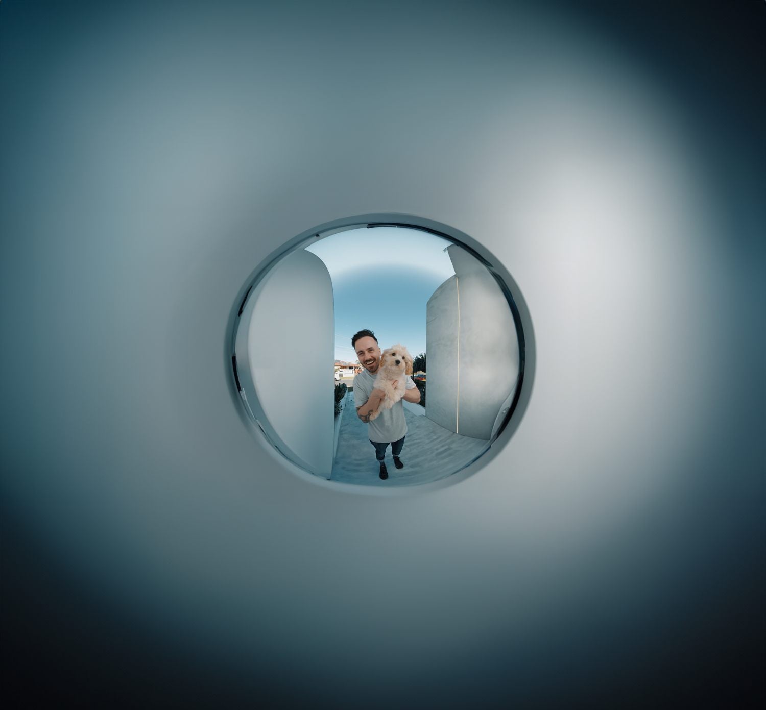 A man holding a puppy at the front door, seen through a fisheye doorbell camera